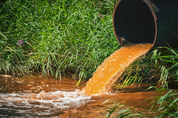 istock Industrial waste in form orange water flowing from pipe into river. 1467216968