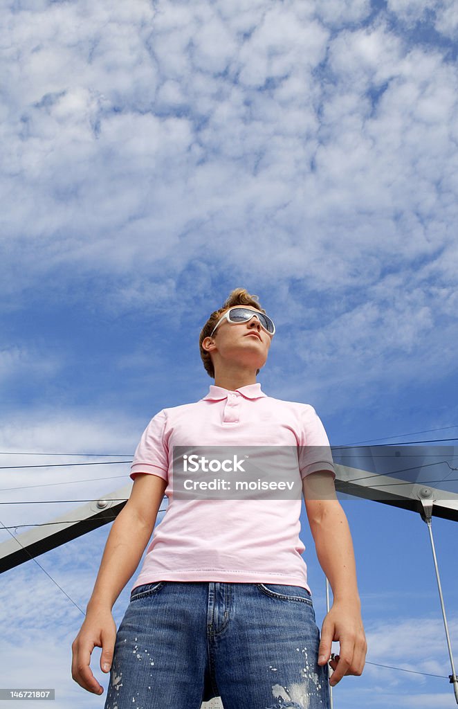 Joven hombre hermoso modelo de pie bajo el nublado cielo. - Foto de stock de A la moda libre de derechos