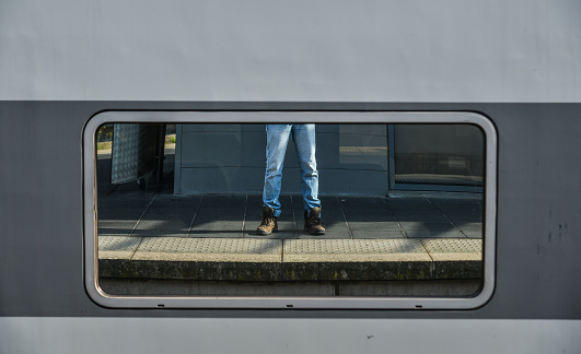 Legs of a man in jean and sneakers, blue jeans in the mirror.