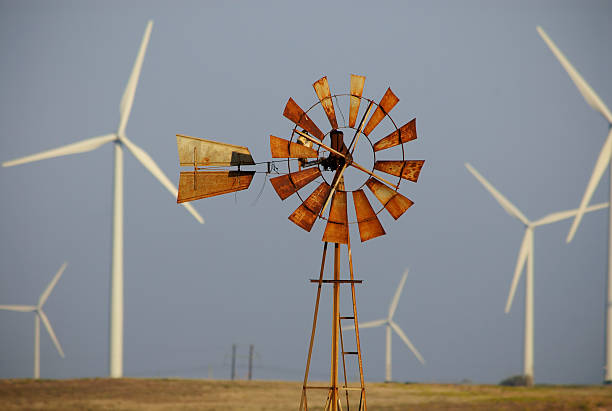 Outdoor photo of rusted windmill surrounded by wind turbines stock photo
