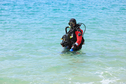 Technical  Diving with Military Rebreather.  Water sports. Handsome scuba diver, men ready to go scuba diving. Dressed in a scuba diving dry suit  Sporting men. Beautiful blue sea in the background.