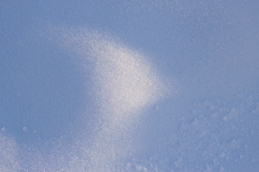 snow surface with sunny spot and blue shadows area as a top view winter backdrop