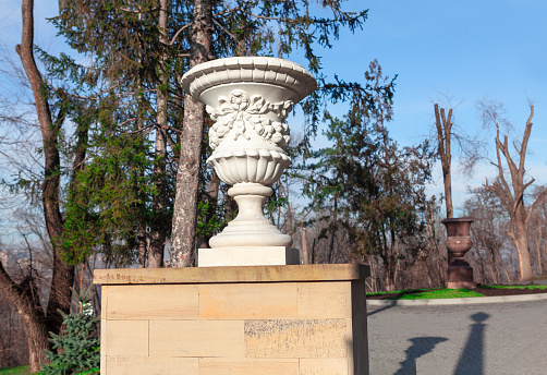 Carved vase flower bed in park . Park garden stone marble flowerpot