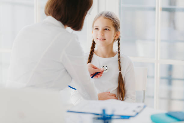 istock Family general practitioner examines child, listens lungs with stethoscope, makes prescription pose in moren hospital office. Ill kid has cold, comes to pediatrician for good advice has health checkup 1467241274