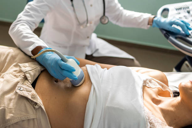 médico examinador mulher madura com dispositivo de scanner de ultrassom - abdómen - fotografias e filmes do acervo