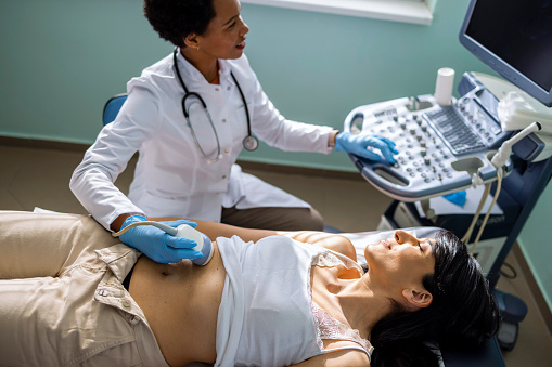 Young Caucasian pregnant woman undergoing abdominal ultrasound scan in clinic