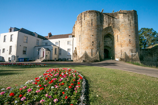 The entrance to Tonbridge Castle in Kent, England. After William the Conqueror took England at the Battle of Hastings in 1066, his kinsman Richard Fitz Gilbert was tasked with guarding the crossing of the River Medway. He built a simple Motte-and-bailey castle. The castle was later besieged in 1088 when Fitz Gilber's descendants rebelled against William's son, King William II. The king had the castle and Tonbridge burnt to the ground in revenge. By 1100, a new wooden castle was replaced with a stone shell keep and in 1295 a stone wall encircled the town. The castle was used to safekeep the great seal of England for a while when King Edward I visited France. In 1793, the mansion was built, and both buildings are now Grade I listed.