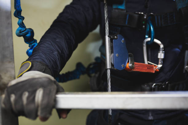 Hand of the wind turbine engineer holding the ladder and protected with the lifeline and climbing fall. stock photo