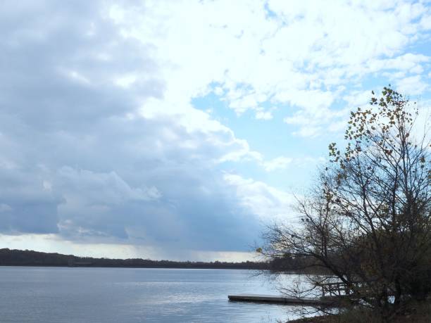 istock Cloudy sky above the smooth lake with leafless trees on the shore. 1467248338