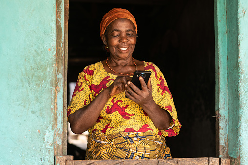 A smiling elderly African woman using her mobile phone