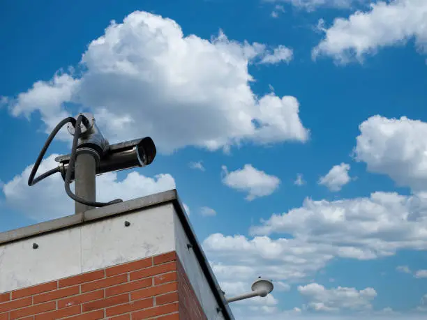 the surveillance camera on a wall of building . security videocamera(CCTV) in a public place.