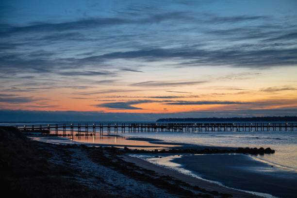 long pier at sea against a sunset sky - ppier imagens e fotografias de stock