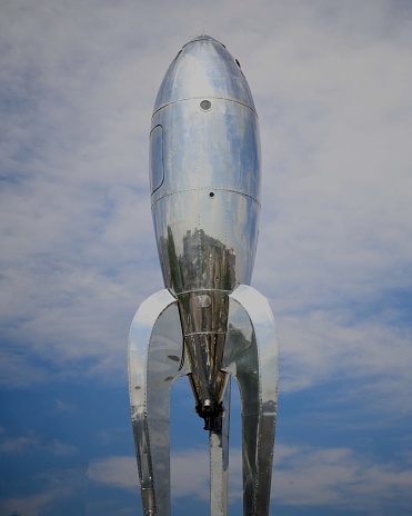 Denver, United States – February 04, 2021: A vertical closeup of a silver space rocket in the sky near another structure in Denver, USA