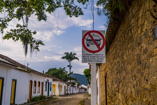 A view of cobbled colonial streets with buildings and a sign saying no car without authorization, Paraty, Brazil