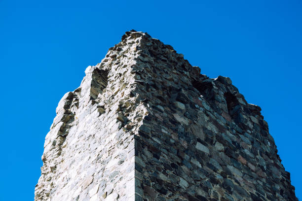 An old ruined tower facade from below in the blue sky background