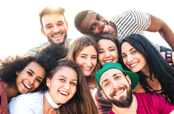 multicultural guys and girls taking funny selfie - happy millenial friendship and life style concept on young multiracial best friends having fun day together at college campus - warm backlight filter - youth organization imagens e fotografias de stock