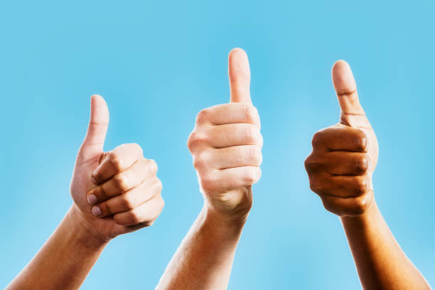 Hands of three diverse people giving the thumbs-up sign stock photo