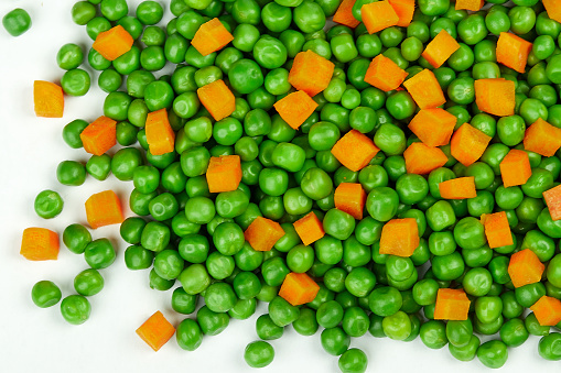 A closeup shot of fresh green peas and cut carrots
