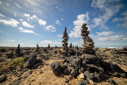 Many balanced stone stackings under a cloudy sky during the daytime