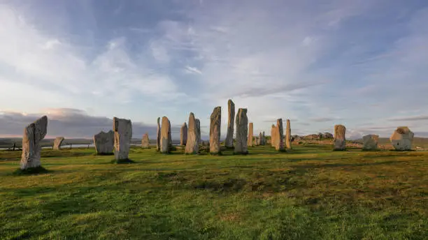 A beautiful shot of Callanish standing stones against blue cloudy sky at sunrise in Isle of Lewis, Scotland