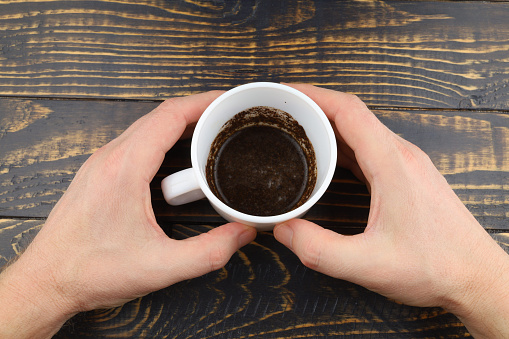 Cup with coffee grounds in hands
