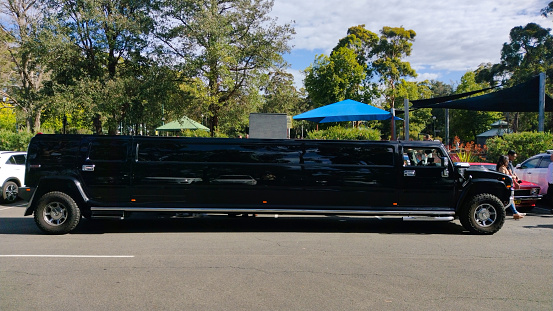 Luxury Stretch Hummer Limousine primarily black in colour, parked outside a community park in South Sydney, NSW Australia