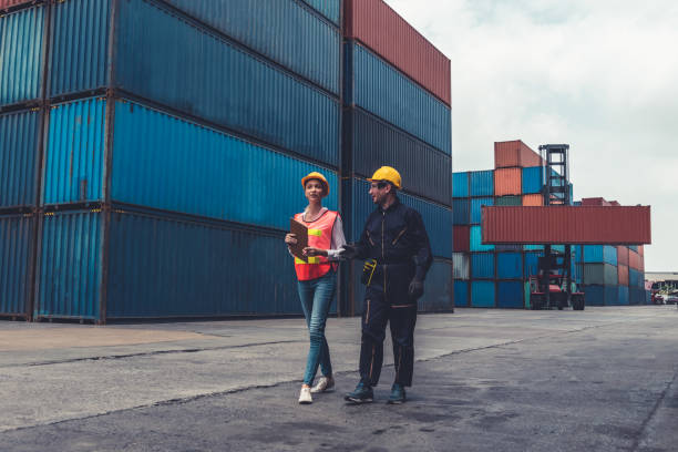 istock Industrial worker works with co-worker at overseas shipping container yard . Logistics supply chain management and international goods export concept . 1467268473