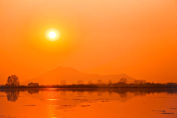Orange sun over serene lake stock photo