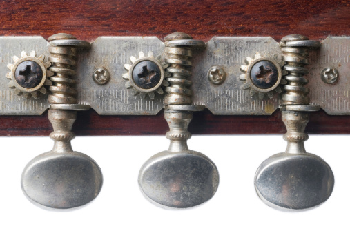 Closeup of a guitar peg head, showing three tuning gears and keys. Isolated on white.