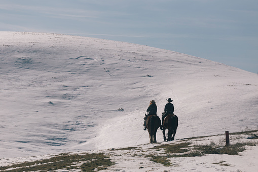 Twin sisters riding horse on sunny winter day in mountains