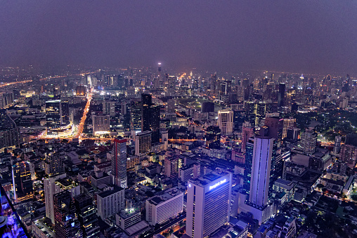 Scenic view of many lit skyscrapers and other buildings in downtown Bangkok, Thailand, from above at night. 22nd of January 2020