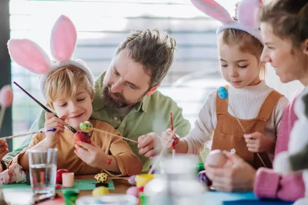 Photo of Happy family with little kids decorating easter eggs.