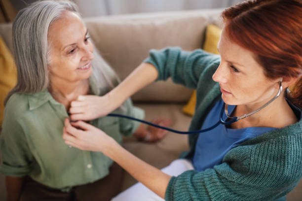 istock Nurse examining senior patient with stethoscope at her home. 1467278879