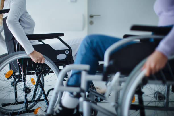 Close-up of young women at wheelchairs in hospital. stock photo