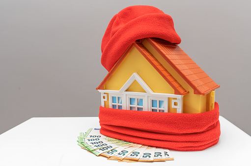 A house wrapped in a scarf and money. Savings and conscious use of resources.