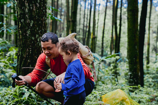 Father and curious toddler son hiking in woods