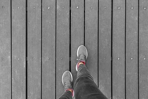 Legs in sneakers on a wooden platform. There is space for text.