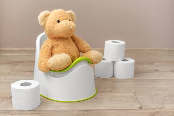 A soft toy sits on a potty. A soft toy sits on a potty. Toilet paper nearby. accustom stock pictures, royalty-free photos & images