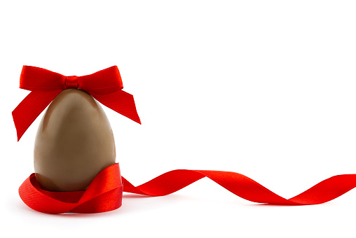 Happy Easter concept. Chocolate easter egg decorated red ribbon with bow isolated on white background with place for your text