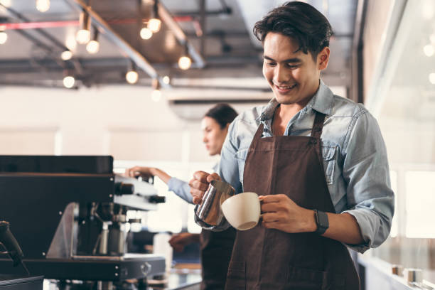 Happy barista Asia man make coffee with team work background at coffee shop Happy barista Asia man make coffee with team work background at coffee shop barista stock pictures, royalty-free photos & images