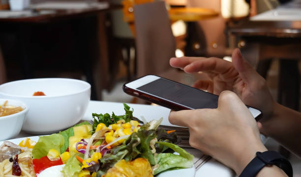 istock Man hand using or looking at his smartphone and having lunch in the restaurant with friends 1467299016