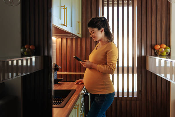 istock Pregnant woman with cellphone in kitchen. 1467300618