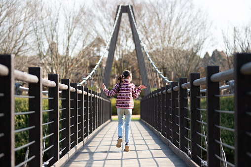 girl walking on suspension bridge