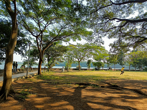 Stock photo of beautiful Rankala lake, old stone retaining wall around the lake few people sitting on retaining and wall and enjoying the view. Picture captured under bright sunlight at Kolhapur.