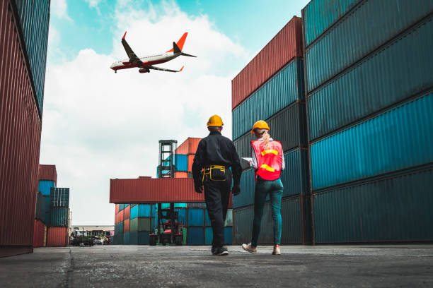 istock Industrial worker works with co-worker at overseas shipping container port . Logistics supply chain management and international goods export concept . 1467306942