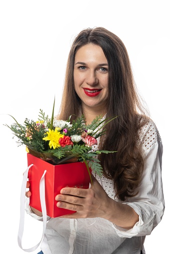 Portrait of a young woman with a bouquet of flowers on a white background.