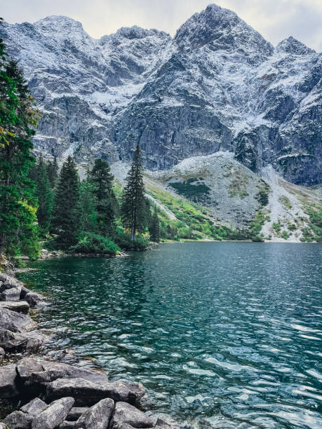 Morskie Oko lake Snowy Mountain Hut in Polish Tatry mountains, Zakopane, Poland. Beautiful green hills and mountains in dark clouds and reflection on the lake Morskie Oko lake Morskie Oko lake Snowy Mountain Hut in Polish Tatry mountains, Zakopane, Poland. Beautiful green hills and mountains in dark clouds and reflection on the lake Morskie Oko lake. Travel tourist destination zakopane stock pictures, royalty-free photos & images