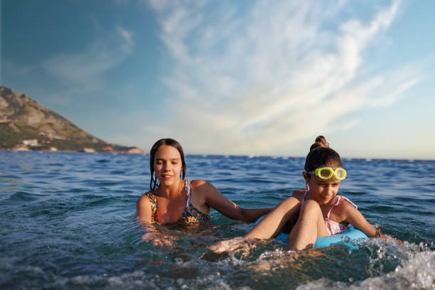 istock Two sisters in bathing suits play with an inflatable ring in the sea 1467333237