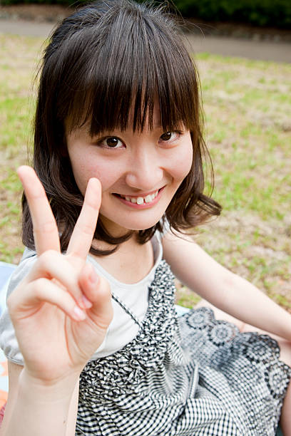 Japanese Girl Makes A Peace Sign Stock Photo - Download Image Now