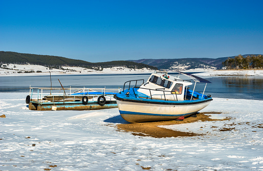 Boats on the shore at mountain dam Batak wintertime. Bulgaria, Europe.
